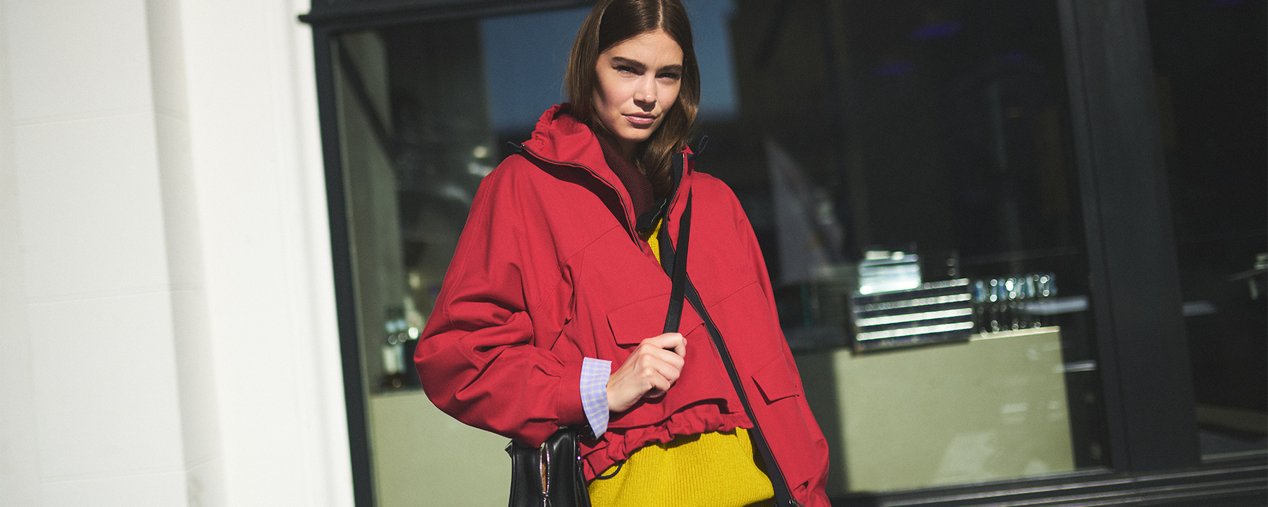 Eine Frau trägt eine rote Jacke und einen gelben Pullover.