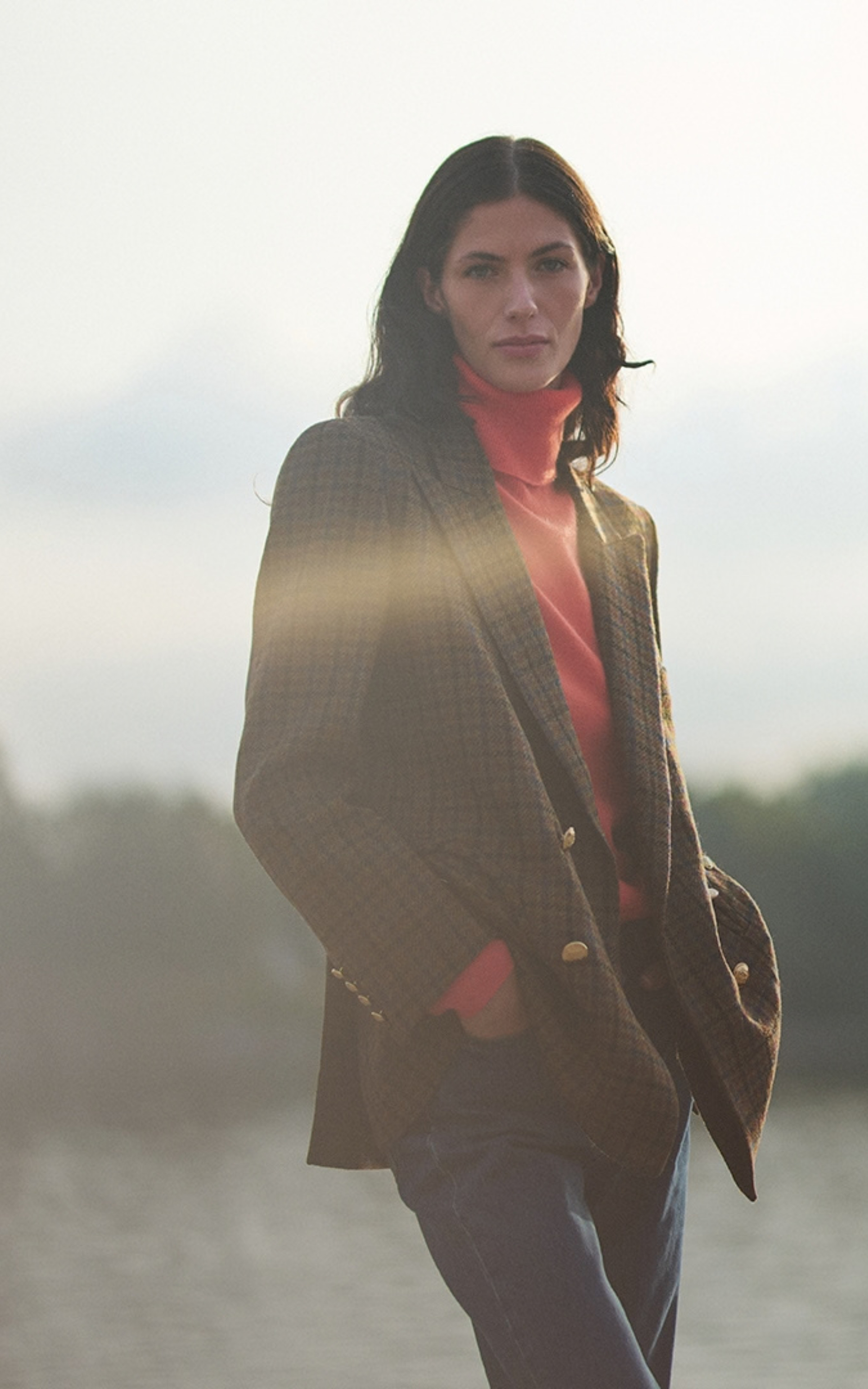 Eine Frau in einem karierten Blazer und rotem Rollkragenpullover outdoors.